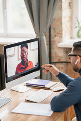 Young confident African woman on computer screen talking to male teacher during online lesson or consultation