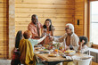 © pressmaster - Happy interracial family of three generations toasting by festive table served with homemade food prepared for dinner