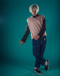 © qunica.com - Young adult man in casual outfit wear looking at camera, holding skateboard near face and standing at studio on blue background