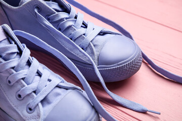 Wall Mural - Pair of stylish shoes with untied laces on pink wooden background, closeup