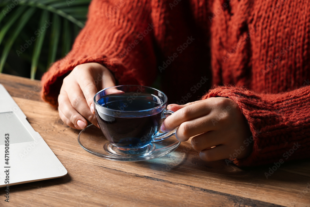 Woman drinking butterfly pea flower tea at table