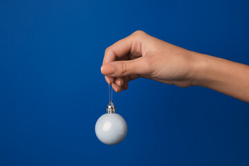 Wall Mural - Female hand with Christmas ball on blue background