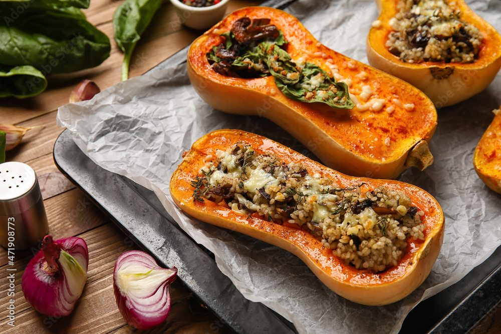 Baking dish with tasty stuffed pumpkins on wooden background