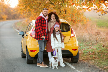 Wall Mural - Parents with little daughter and cute dog near yellow car on autumn day