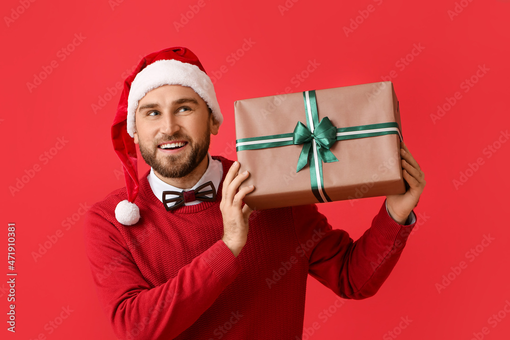 Happy young man with Christmas gift on color background