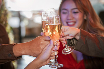 close up glasses of clinking glasses of champagne with lighting. Dinner party with drinking of champagne. hands holding clear glass with alcohol in yellow shine reflect.