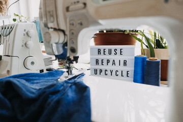 Wall Mural - Reuse, repair, upcycle text on light board on sewing machines background. Stack of old jeans, Denim clothes, scissors, thread and sewing tools in sewing studio. Denim Upcycling Ideas, Using Old Jeans