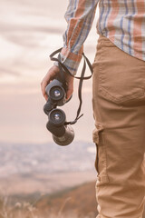 Wall Mural - The traveler lowered his hand with the binoculars. Natural landscape in the background.