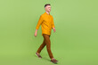 Full body profile side photo of cheerful mature man walk vacation isolated over green color background