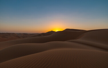 Wall Mural - Sunset in the arabian desert with rolling sand dunes in Abu Dhabi, United Arab Emirates