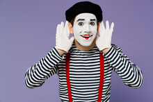 Fun Young Mime Man With White Face Mask Wears Striped Shirt Beret Holding Hands Near Ears Try To Hear You Overhear Listening Intently Isolated On Plain Pastel Light Violet Background Studio Portrait.