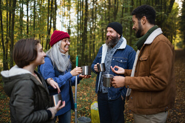 Wall Mural - Diverse group of happy volunteers cleaning up forest, having break, drinking tea and talk together.