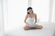 © u photostock - Asia woman sitting on the bed in morning with headphone and laptop
