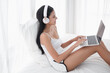 © u photostock - Asia woman sitting on the bed in morning with headphone and laptop