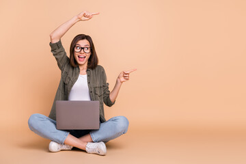 Poster - Photo of curious lady sit floor hold pc direct finger empty space wear specs khaki shirt isolated beige color background