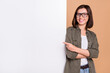 © deagreez - Photo of cheerful lady direct forefinger placard board empty space wear specs khaki shirt isolated beige color background