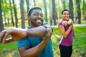 Young man and beautiful woman doing stretching exercises outdoors