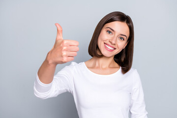 Wall Mural - Photo of cute brunette young lady show thumb up to camera wear white jumper isolated on grey color background