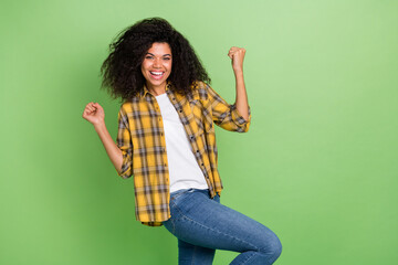 Sticker - Photo of hooray curly hairdo millennial lady hands fists wear yellow shirt jeans isolated on green color background