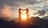Couple in love making hart shape at sunset in mountains