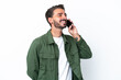 © luismolinero - Young caucasian man isolated on white background keeping a conversation with the mobile phone