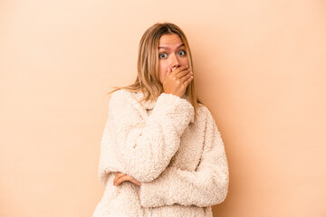 Wall Mural - Young caucasian woman isolated on beige background scared and afraid.