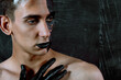 © Denis - Portrait of a young man with unusual makeup. The guy is posing without a T-shirt. Black paint on the face.