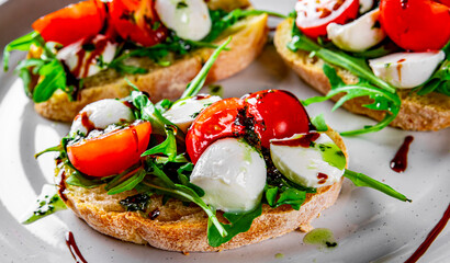 Wall Mural - Italian bruschetta with roasted tomatoes, mozzarella cheese, balsamic vinegar and herbs on plate