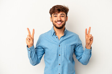 Wall Mural - Young mixed race man isolated on grey background showing victory sign and smiling broadly.