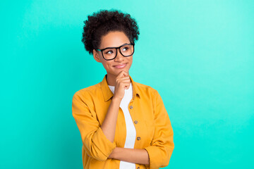 Photo of young black girl hand touch chin dreamy curious thoughtful look empty space isolated over turquoise color background