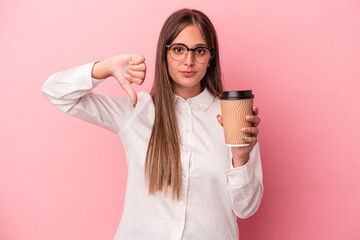 Wall Mural - Young business caucasian woman holding a take away isolated on pink background showing a dislike gesture, thumbs down. Disagreement concept.