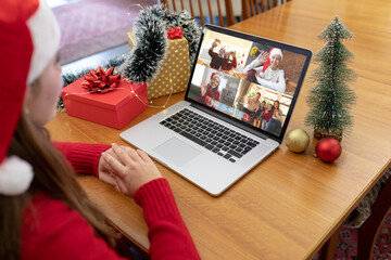 Canvas Print - Caucasian woman in santa hat making laptop christmas group video call with family and friends