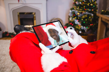 Canvas Print - Santa claus making tablet christmas video call with smiling african american boy in santa hat