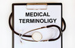 On the tablet for writing the text MEDICAL TERMINOLIGY, around it is wrapped a stethoscope.