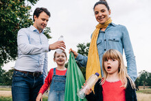 Daughters Collecting Plastic Bottles With Parents In Park