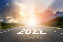 Start To New Year 2022 Concept. Start 2022 Written On Highway Road In The Middle Of Empty Asphalt Road With Sunset Or Sunrise Light Above Asphalt Road.