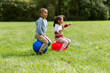 childhood, leisure and people concept - happy children bouncing on hoppers or bouncy balls at park
