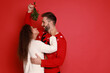 © New Africa - Lovely couple under mistletoe bunch on red background. Space for text