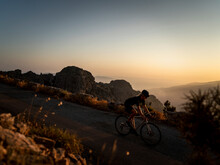 Athlete Cycling On Mountain Road At Sunset