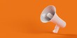 White megaphone or bullhorn floating over orange background, business announcement or communication concept with copy space