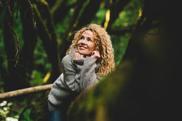 Portrait of attractive caucasian woman smiling and enjoying the green woods forest outdoors. People and nature environmental lifestyle travel. Beautiful female smile laying on a trunk tree