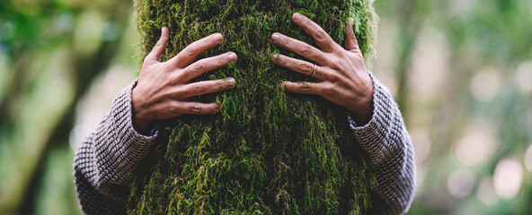 Wall Mural - Nature lover hugging trunk tree with green musk in tropical woods forest. Green natural background. Concept of people love nature and protect from deforestation or pollution or climate change