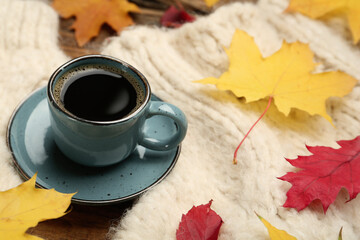 Poster - Cup of hot coffee, sweater and autumn leaves on table, space for text