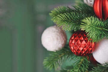 Wall Mural - Round red christmas ornament bauble on tree in front of green background with copy space