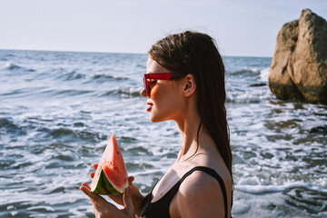 Wall Mural - woman in black swimsuit with watermelon by the ocean