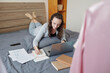 © DragonImages - Woman enjoying working from home, checking reports and agreements on laptop and taking notes in planner