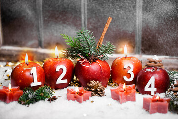 Beautiful card with advent candles and christmas apples in front of old window in snow. 3rd advent, 3 candles burning. Christmas Eve.