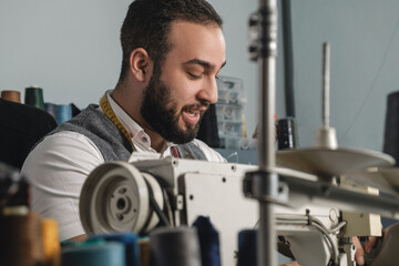 Middle Eastern young man working at his tailor shop. Small business or self-employed concept