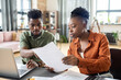© pressmaster - Young blackwoman showing document to husband while discussing tax papers with him at home