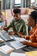 © pressmaster - Serious young African American couple sitting at table and entering bill data while filling tax form online